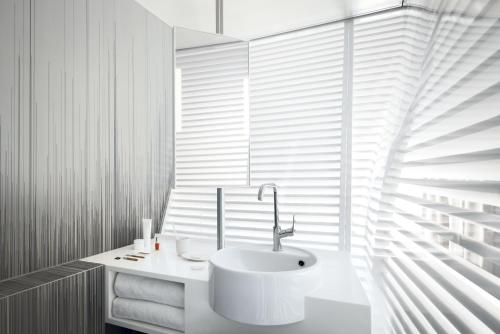 a white bathroom with a sink and a window at Okko Hotels Grenoble Jardin Hoche in Grenoble