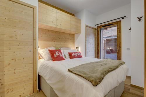 une chambre avec un grand lit blanc avec des oreillers rouges dans l'établissement Echo du Pleney A003, à Morzine