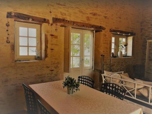 Cette chambre comprend une table, des chaises et des fenêtres. dans l'établissement Une Maison de campagne en Bourgogne du Sud, à Tournus