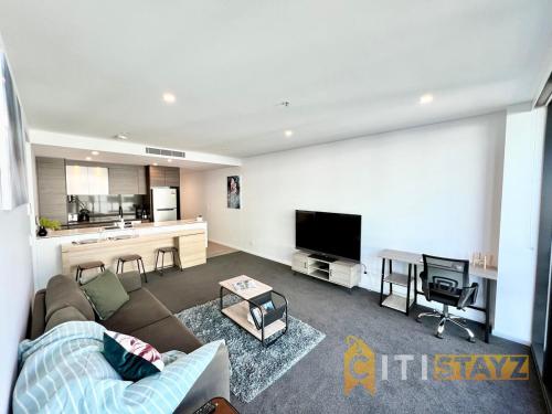 a living room with a couch and a tv at Light & Lovely in Canberra's CBD - 1BR Apt w/Carsp in Canberra