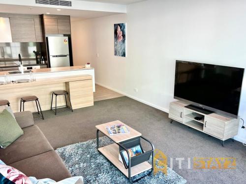 a living room with a large flat screen tv at Light & Lovely in Canberra's CBD - 1BR Apt w/Carsp in Canberra