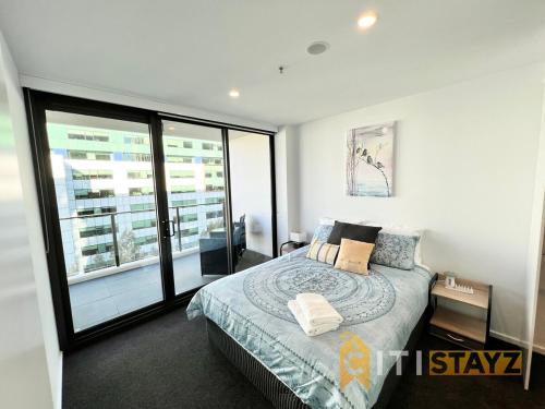 キャンベラにあるLight & Lovely in Canberra's CBD - 1BR Apt w/Carspのベッドと大きな窓のある寝室
