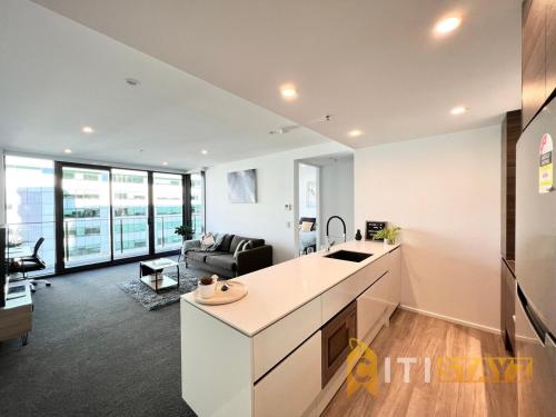 an open kitchen and living room with a couch at Light & Lovely in Canberra's CBD - 1BR Apt w/Carsp in Canberra