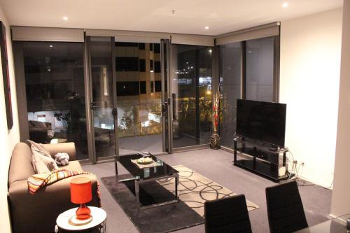 a living room with a couch and a flat screen tv at Perfectly Located Modern Apartment - Canberra CBD in Canberra