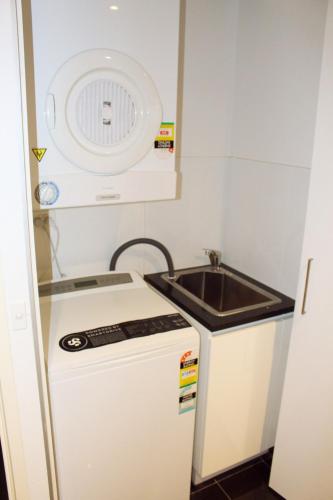a small kitchen with a sink and a small refrigerator at Perfectly Located Modern Apartment - Canberra CBD in Canberra