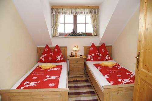 two beds in a attic room with red pillows at Landhaus Gartler in Mauterndorf