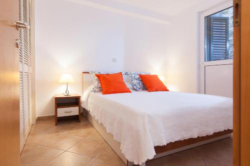 a bedroom with a bed with orange pillows and a window at Villa Helena in Podgora