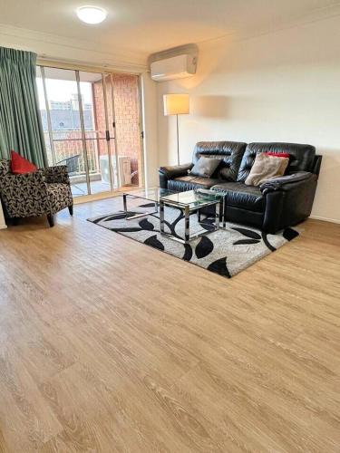 a living room with a black couch and a table at Beautiful & enclosed, 1 bd 1 bth - close to CBR Hospital in Phillip