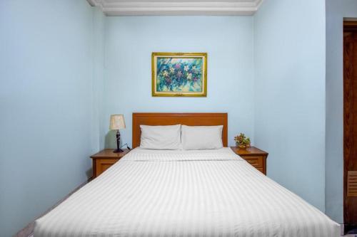 uma cama num quarto com uma parede azul em Hotel Ardellia em Bandung