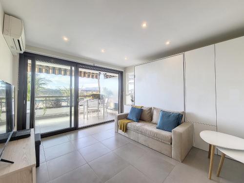un salon avec un canapé et une grande fenêtre dans l'établissement Nestor&Jeeves - GRAND SUD TERRASSE - Pool - Free parking, à Nice