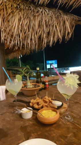 uma mesa com dois copos de margaritas e alguma comida em Casinha no Sal - Tangaroa Residencial em Salinópolis