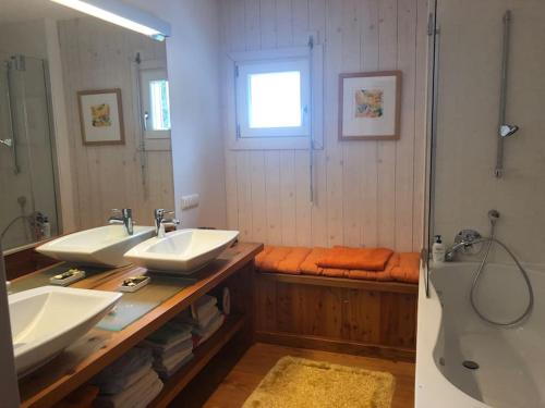 uma casa de banho com 2 lavatórios, uma banheira e um espelho. em Teichalm Lodge Landhaus em Fladnitz an der Teichalm
