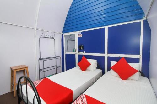2 camas en una habitación pequeña con almohadas azules y rojas en A4 Residence Colombo Airport -by A4 Transit Hub - free pickup & drop Shuttle Serviceトランジットホテルトランジットホテル, en Katunayake