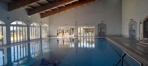 an indoor swimming pool with blue water in a building at Oásis do João e da Dalila in Portimão