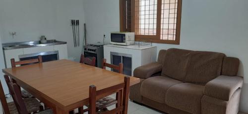 sala de estar con mesa, sofá y cocina en Casa Residencial Duque de Caxias, en Arroio do Sal