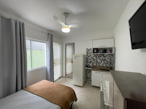 Habitación con cama y cocina con nevera. en Apartamento Onda Azul, en Balneário Camboriú