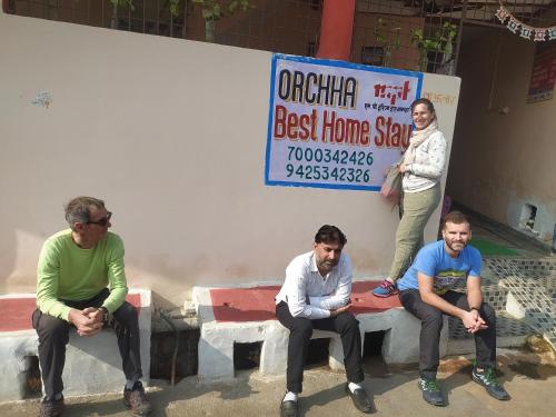 a group of men sitting on a bench in front of a sign at Orchha Best Homestay in Orchha