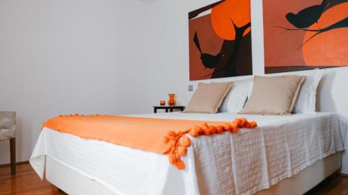 a white bed with an orange blanket on it at Quinta de Fiães in Vilar de Maçada