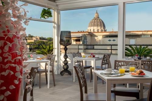 a restaurant with tables and chairs and a view of a dome at Fragrance Hotel St. Peter in Rome