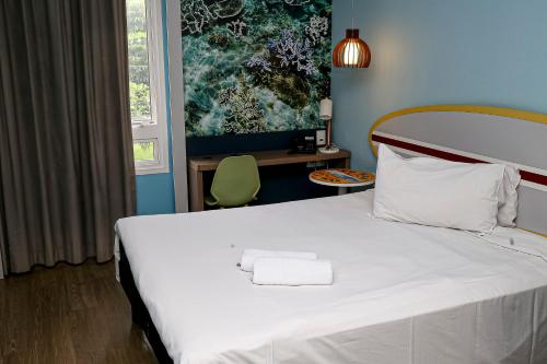 a bedroom with a white bed with a towel on it at Delphin Surf Hotel in Guarujá