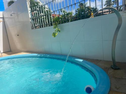 a swimming pool with a water hose attached to a wall at Pousada Mar do Sonho Praia in Ipojuca