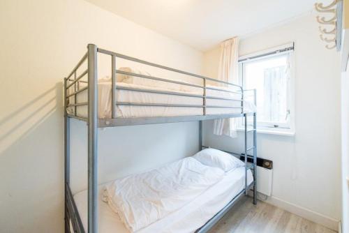 1 dormitorio con 2 literas y ventana en Amelander Kaap appartement 1, en Hollum