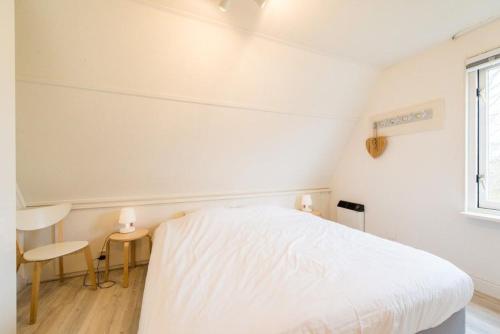a white bedroom with a bed and a window at Amelander Kaap 1 in Hollum