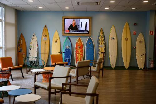 a room with a bunch of surfboards on the wall at Delphin Surf Hotel in Guarujá