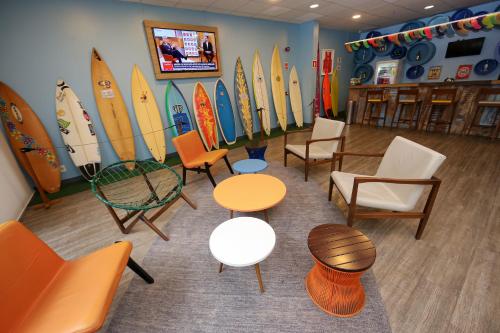 a room with chairs and tables and surfboards on the wall at Delphin Surf Hotel in Guarujá
