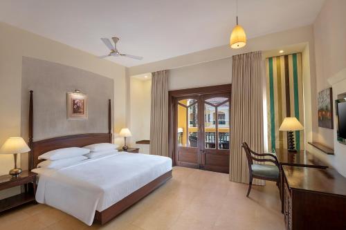 1 dormitorio con 1 cama blanca grande y escritorio en Country Inn & Suites by Radisson, Goa Candolim, en Candolim