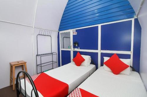 two beds in a small room with blue and red pillows at Airport A4 Transit Hub - Eco Chalets in Katunayake