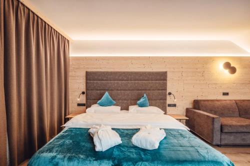 een slaapkamer met een groot bed en handdoeken bij Hotel Plan De Gralba - Feel the Dolomites in Selva di Val Gardena