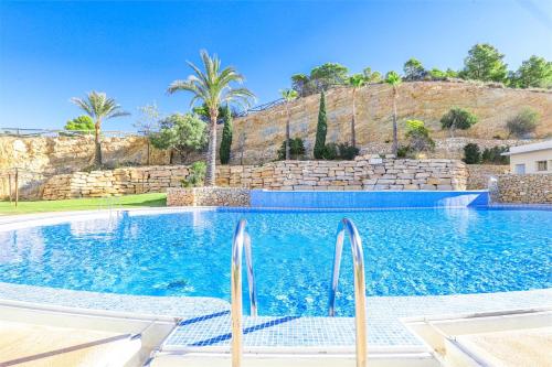 a swimming pool in a villa with palm trees at Large and sunny all-day balcony with stunning sea views in Benidorm
