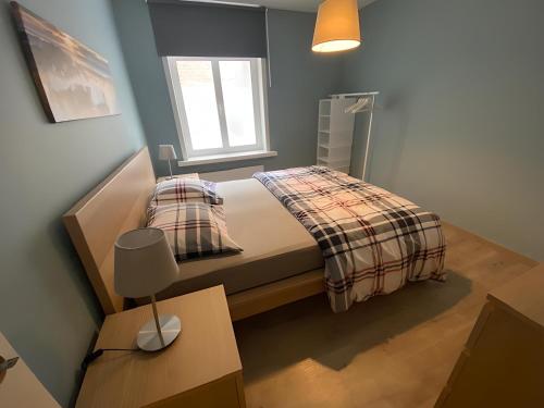 a small bedroom with a bed and a window at 1 slaapkamer logie met extra zetelbed in leefruimte in Middelkerke