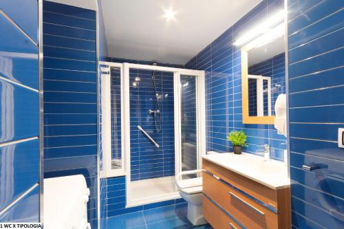 y baño de azulejos azules con aseo y ducha. en Valentia Apartments - Mercado Central, en Valencia