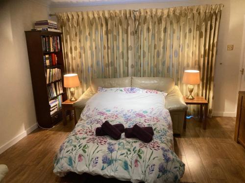 Un dormitorio con una cama con dos zapatos. en Spacious bungalow/private garden-sleeps up to 6, en Marple