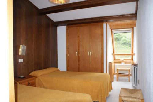 a small room with two beds and a window at Hostal Los Valles in Bielsa