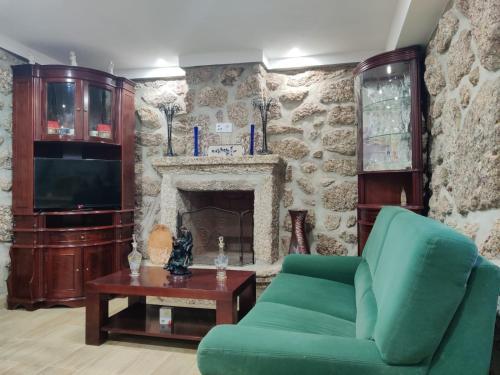 a living room with a green couch and a fireplace at Casa Carlinhos da Carreira in Terras de Bouro