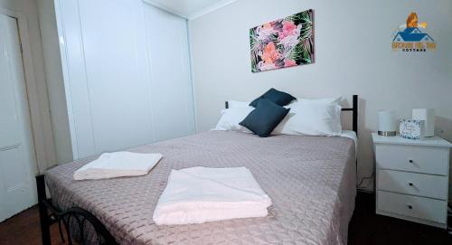 1 dormitorio con 1 cama con 2 toallas en Broken Hill Inn Cottage, en Broken Hill