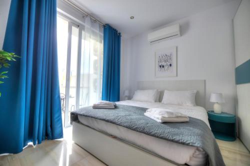 Schlafzimmer mit einem Bett mit blauen Vorhängen und einem Fenster in der Unterkunft Modern and bright 2bedroom with terrace SARD1-1 in St Julian's