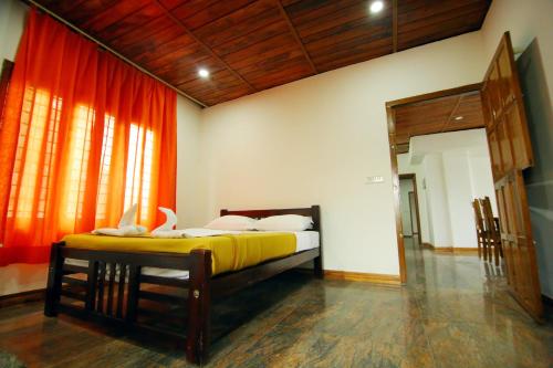 1 dormitorio con 1 cama en una habitación con cortinas de color naranja en AYURGREEN HERITAGE, en Kattappana