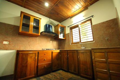cocina con armarios de madera, fregadero y ventana en AYURGREEN HERITAGE, en Kattappana