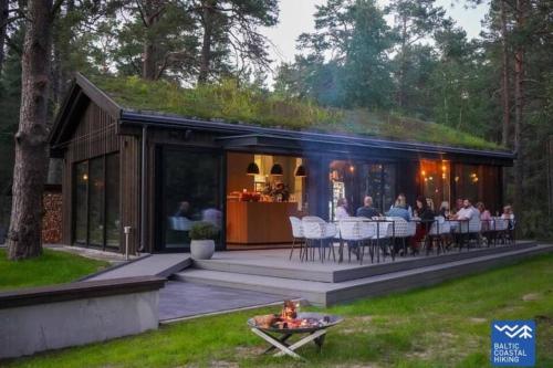 ein Haus mit einer Gruppe von Menschen, die auf dem Deck sitzen in der Unterkunft Seaside_albatross in Ķesterciems