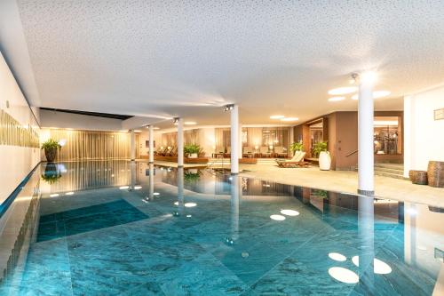 an indoor pool in a hotel with columns and a lobby at Kitzbühel Residences in Kitzbühel