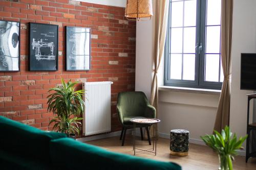 a living room with a brick wall and a green chair at RedCity LOFT 303 in Żyrardów