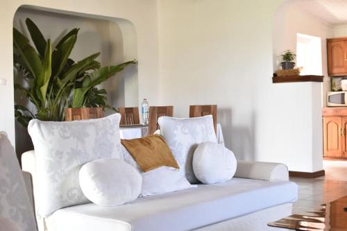 biała kanapa z białymi poduszkami w salonie w obiekcie Villa paisible proche des rizières w Antananarywie