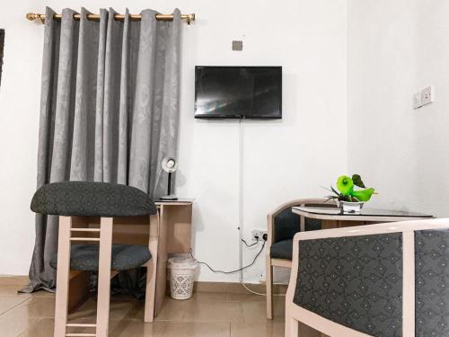 - un salon avec deux chaises et une télévision dans l'établissement Hill View Hotel West Airport, à Accra