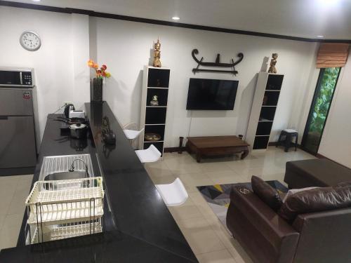 a living room with a couch and a tv at BEA Privileged Apartment in Lamai