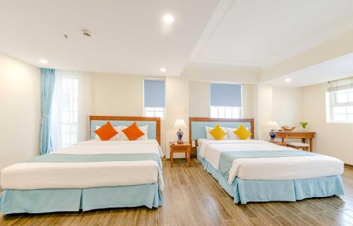 two beds in a room with wooden floors and windows at Pavillon Garden Hotel in Nha Trang