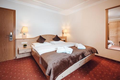 a bedroom with a large bed with towels on it at Hotel Plan de Gralba - das Berghotel in Selva di Val Gardena
